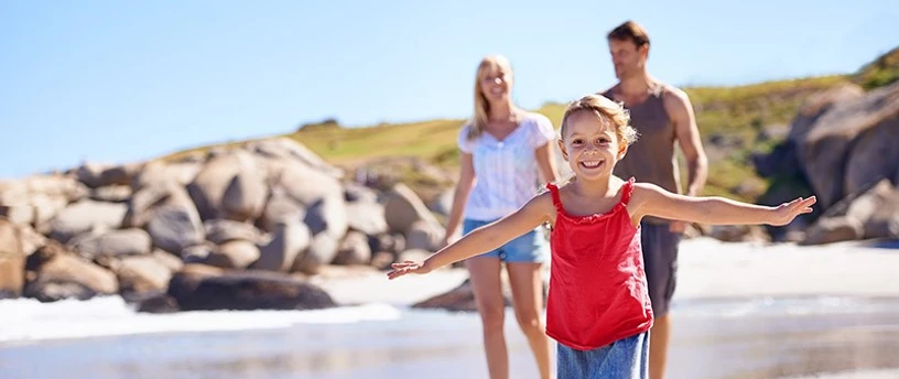Smilende pige med sine forældre ved strand