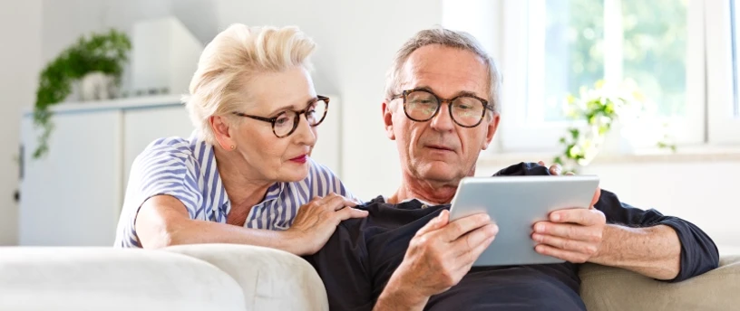 ældre ægtepar med tablet og tryghed i økonomien